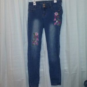 Blue jeans with flower embroidered on the front.
